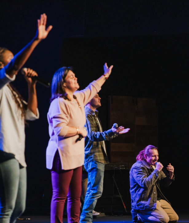 Worship team singing with hands raised