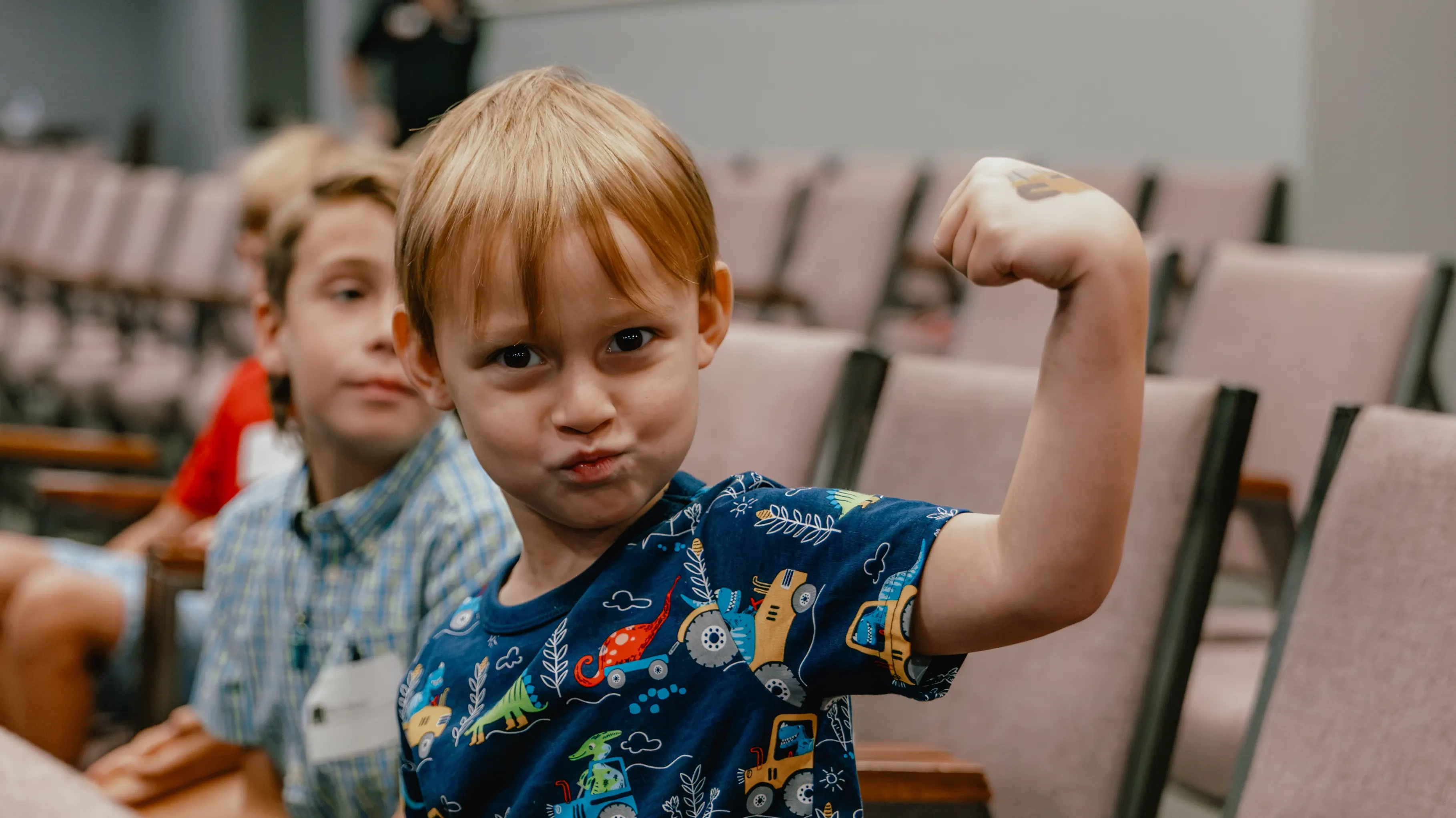 Boy flexing his arm in the church auditorium