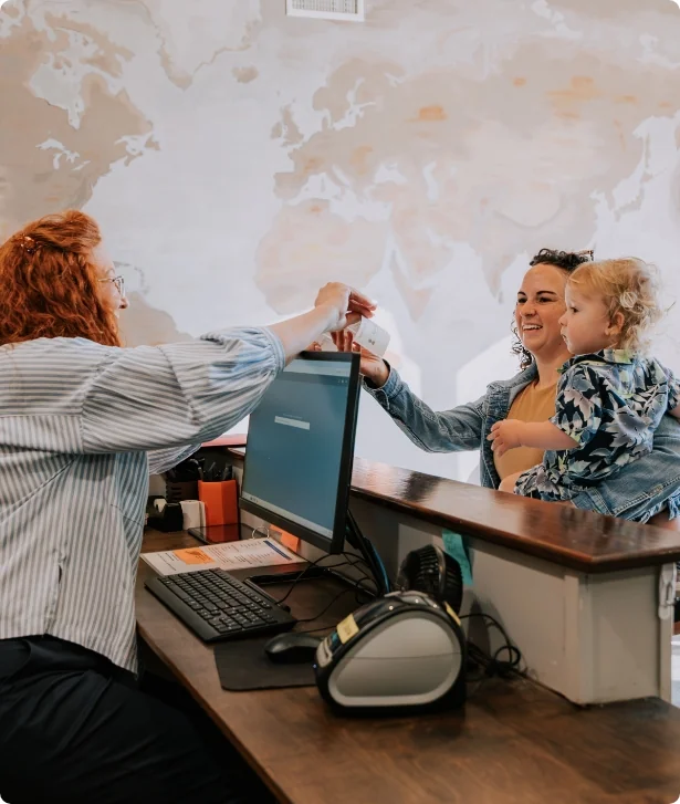 Volunteer checking in a mother and her child at the welcome desk